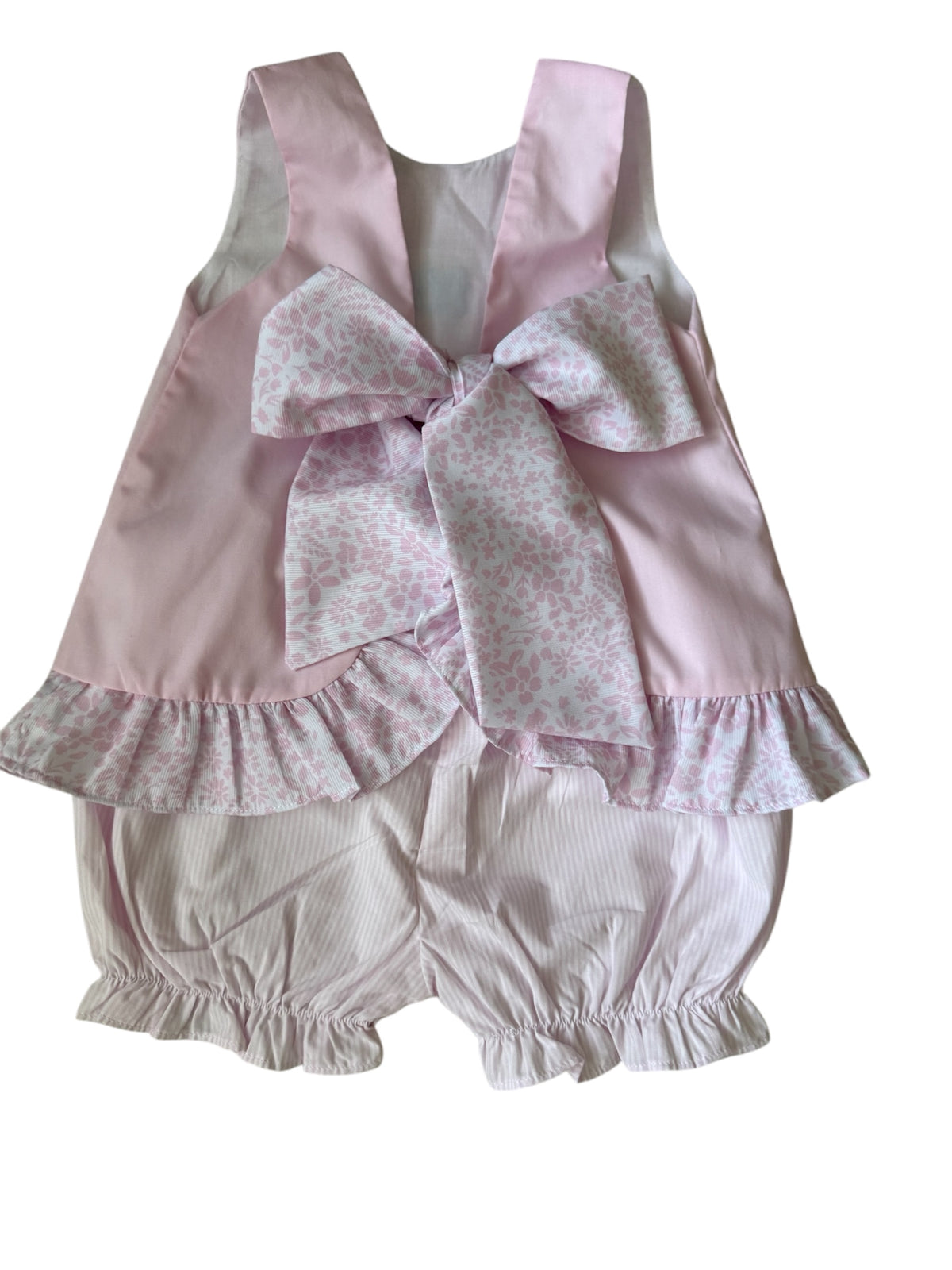 Pink baby outfit with a large bow on a white background