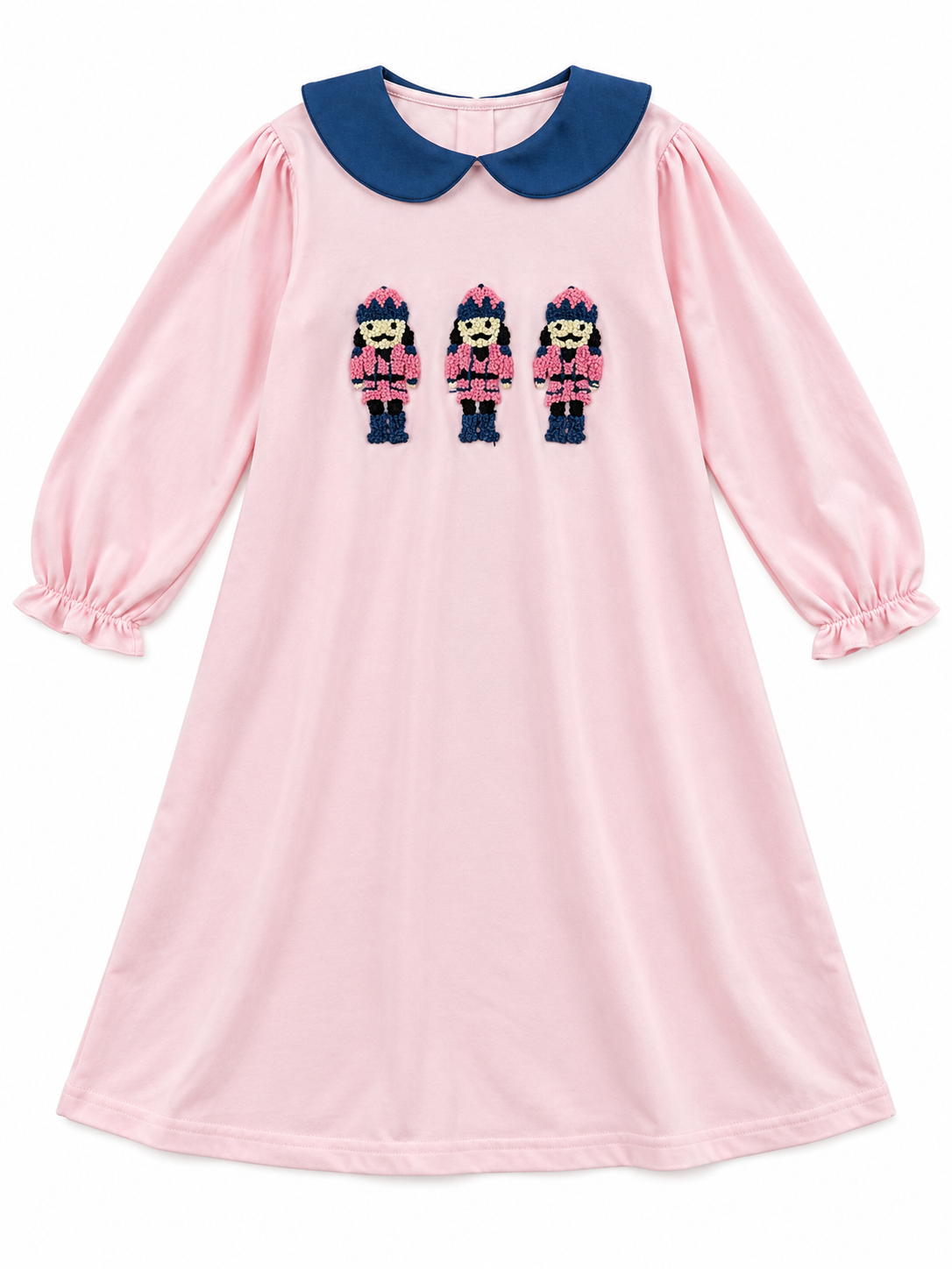 Pink girls’ Christmas dress with navy Peter Pan collar, long sleeves, and three embroidered nutcracker soldiers on the front.